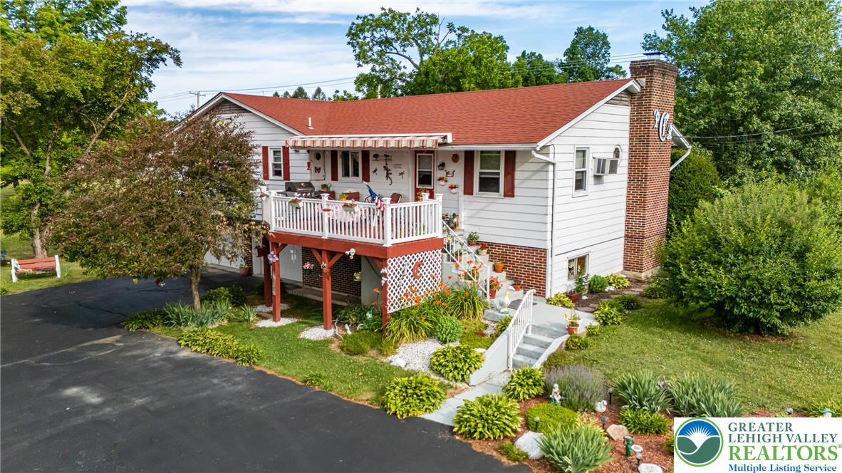 A classic two-story residence with white siding, a red roof, and a welcoming porch, nestled amidst mature trees.