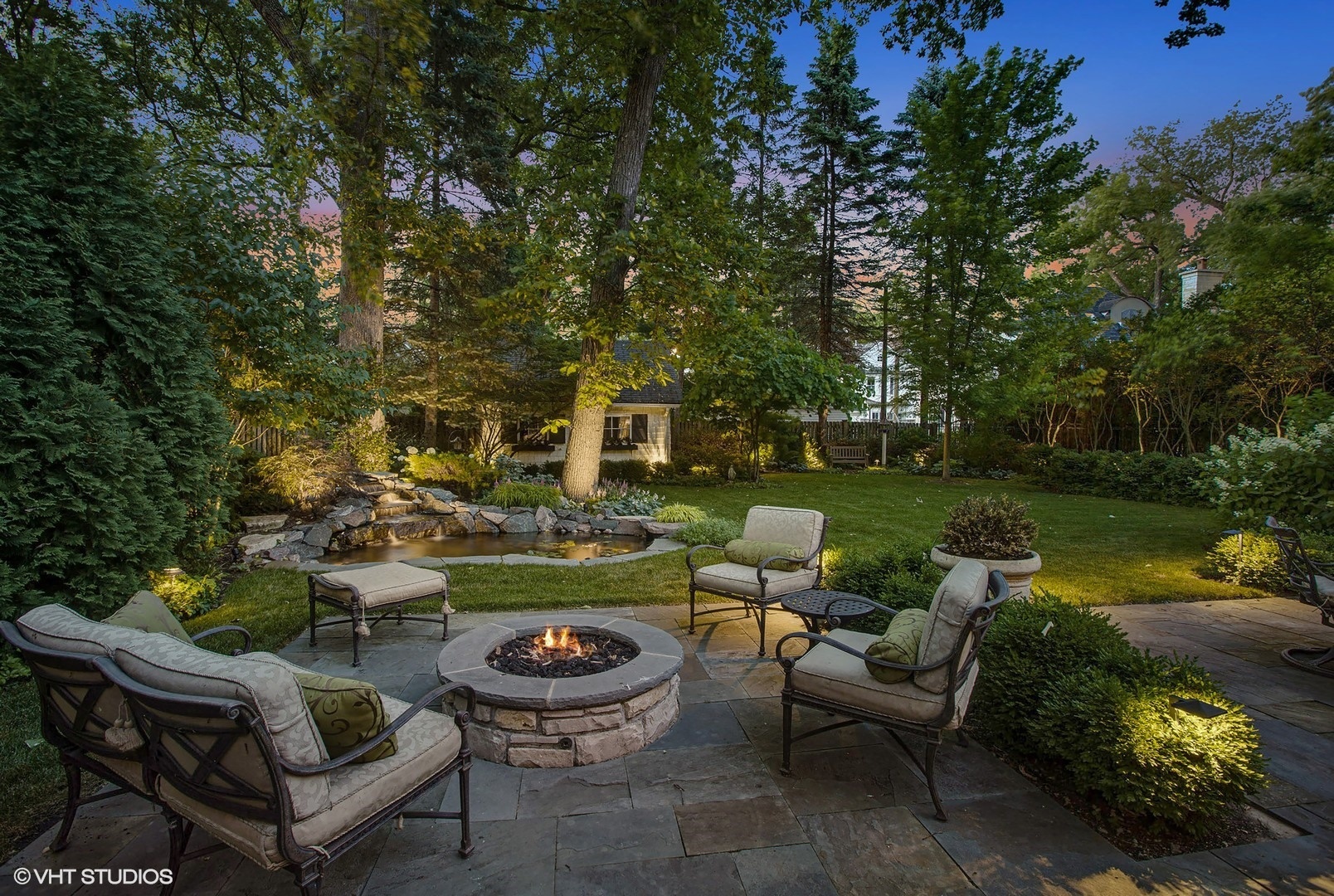 373 Elder Lane Winnetka, IL 60093 - Photo 2 of 53 a view of a patio with couches table and chairs under an umbrella with large trees