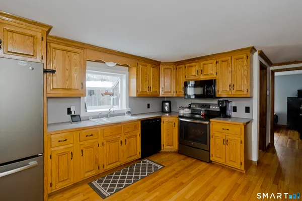 a kitchen with stainless steel appliances granite countertop a stove a sink dishwasher and a microwave oven with cabinets