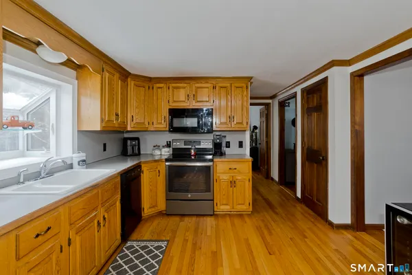 a kitchen with stainless steel appliances a sink cabinets and a wooden floor