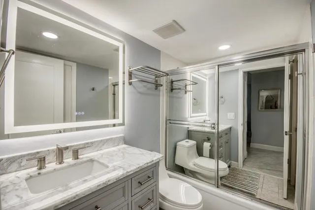 a bathroom with a sink vanity granite toilet and shower