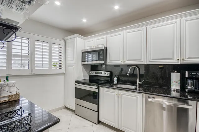 a kitchen with stainless steel appliances granite countertop white cabinets and window