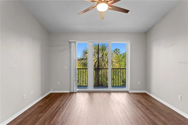 an empty room with wooden floor fan and windows