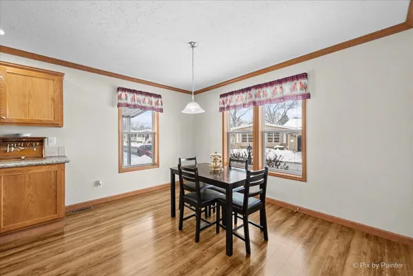 a kitchen with stainless steel appliances granite countertop a stove refrigerator a dining table and chairs with wooden floor