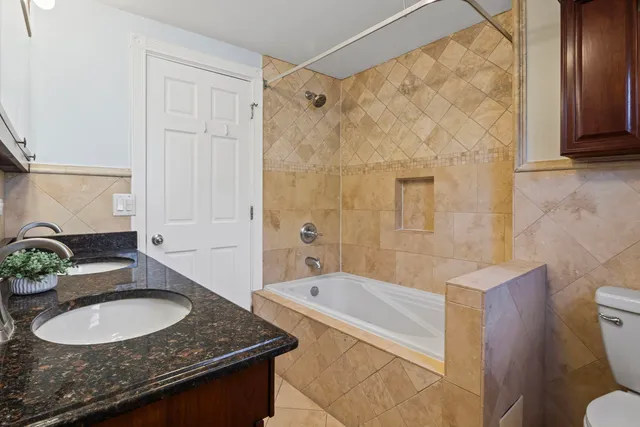 a bathroom with a granite countertop sink a toilet a mirror and shower