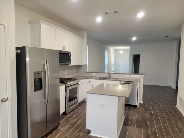 a kitchen with kitchen island a sink stove and refrigerator