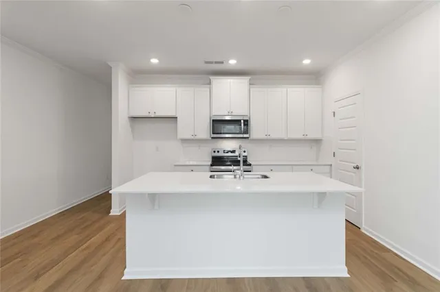 a kitchen with kitchen island sink stove and cabinets