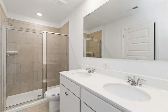 a bathroom with a shower sink vanity mirror and toilet