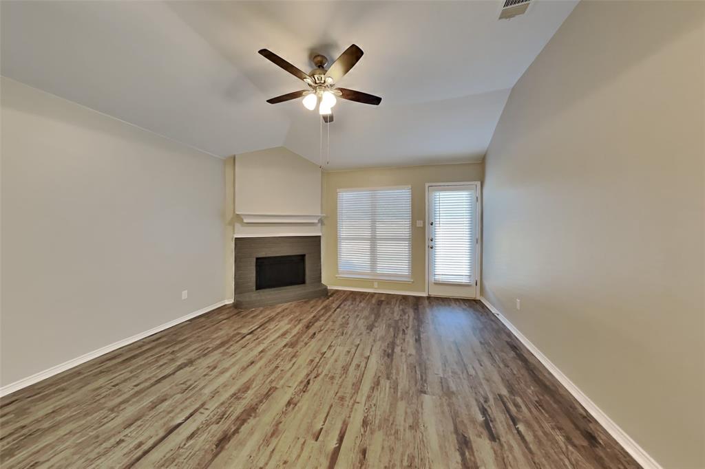 314 South Chestnut Street Forney, TX 75126 - Photo 2 of 18 Unfurnished living room featuring wood finished floors, vaulted ceiling, a brick fireplace, and ceiling fan