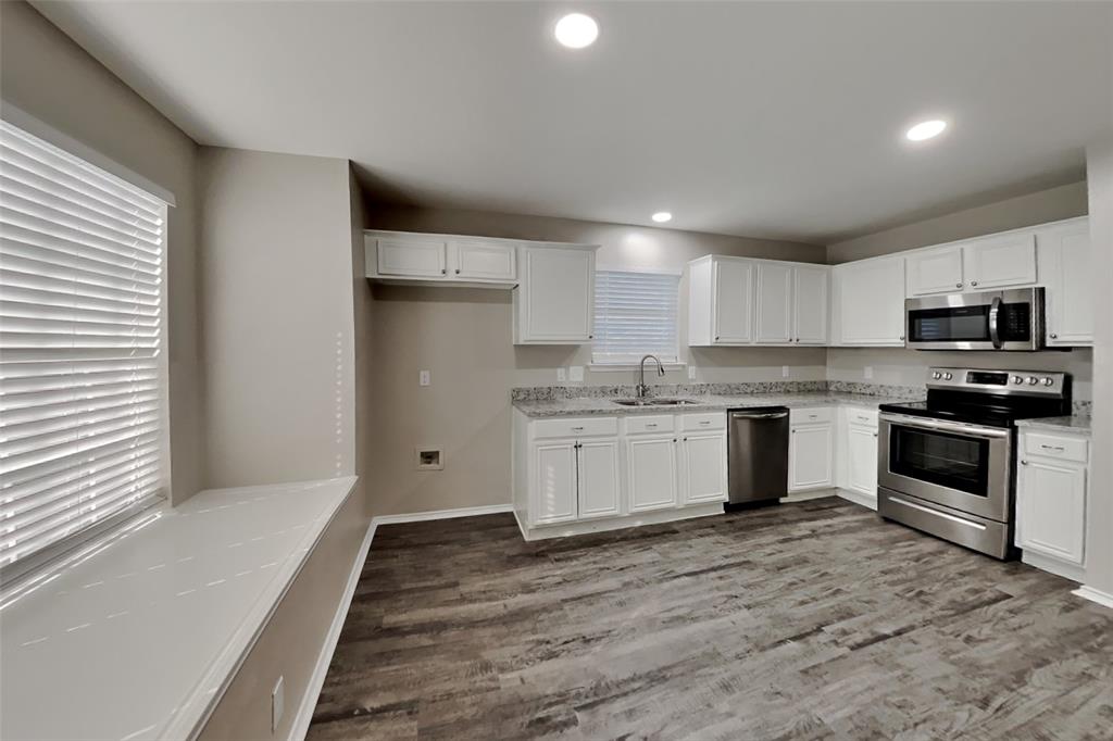 314 South Chestnut Street Forney, TX 75126 - Photo 3 of 18 Kitchen with stainless steel appliances, white cabinetry, dark wood-type flooring, recessed lighting, and light stone counters