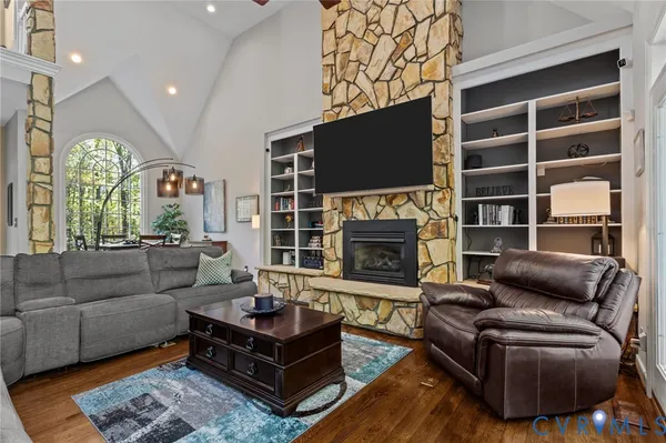 a kitchen with stainless steel appliances granite countertop a stove top oven a refrigerator a sink and white cabinets with wooden floor