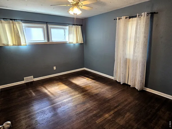 an empty room with wooden floor and windows
