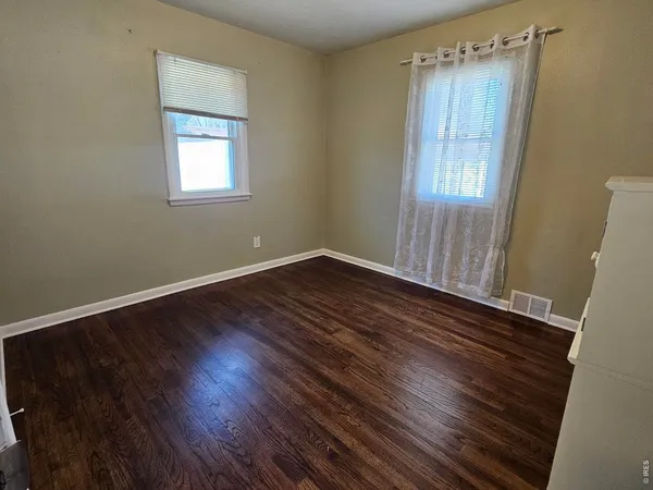 a view of an empty room with wooden floor and closet