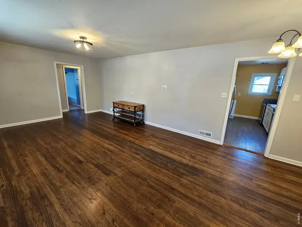 an empty room with wooden floor and mirror