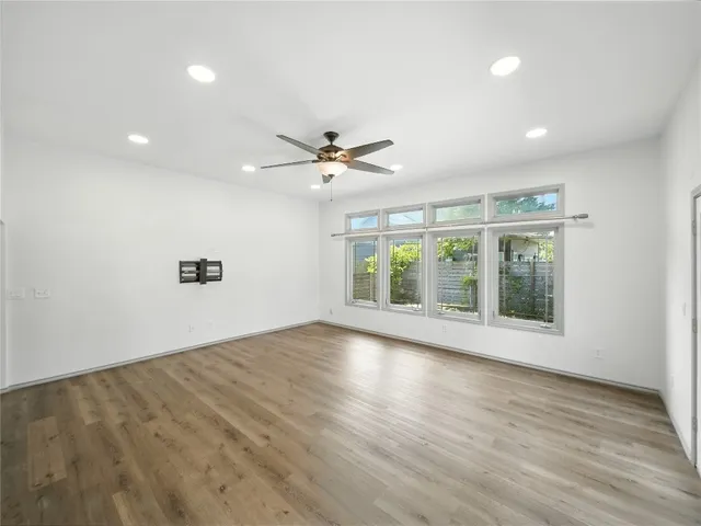 a view of an empty room with a window and wooden floor