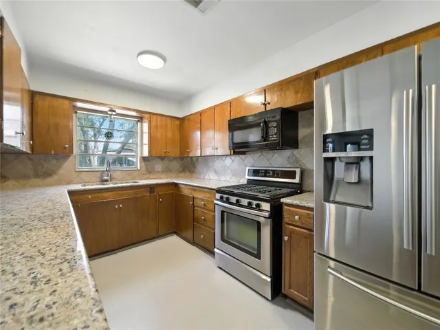 a kitchen with stainless steel appliances granite countertop a stove a sink dishwasher a refrigerator and a microwave oven