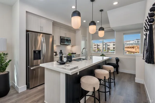 a kitchen with a dining table stainless steel appliances and wooden floor