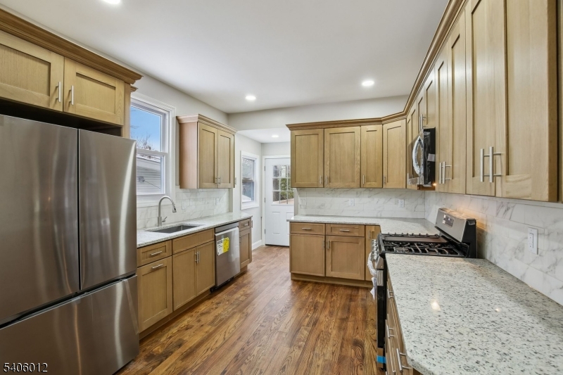 99 Lincoln Street Montclair, NJ 07042 - Photo 16 of 28 a large kitchen with stainless steel appliances granite countertop a refrigerator a sink dishwasher a stove and white countertops with wooden floor