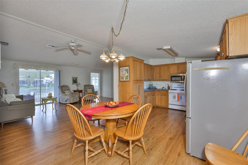980 7th Street Northwest, Unit 16 Largo, FL 33770 - Photo 5 of 35 a dining room with wooden floor a chandelier a wooden table and chairs