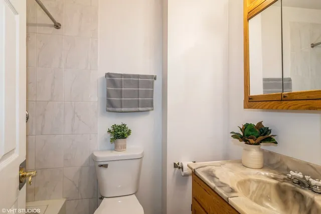 a bathroom with a granite countertop sink a toilet and with mirror
