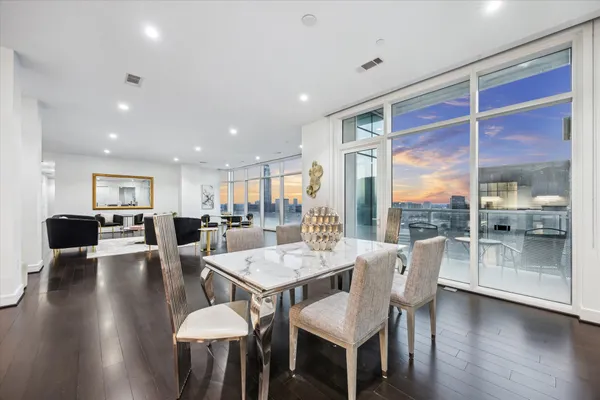 a dining room with wooden floor and large windows