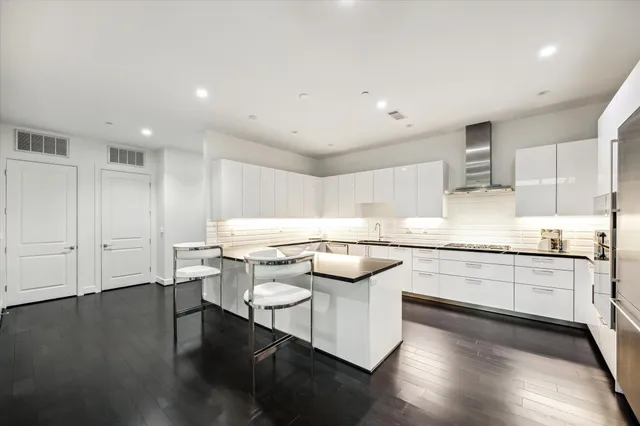 a kitchen with stainless steel appliances white cabinets and wooden floor