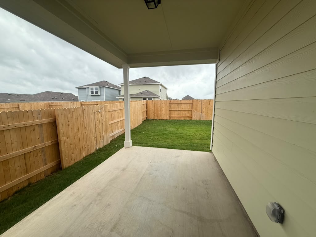2601 Foss Road Manor, TX 78653 - Photo 24 of 40 A covered concrete patio overlooks the grassy backyard enclosed by wooden fencing.