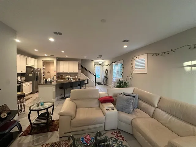 a living room with furniture kitchen view and a window