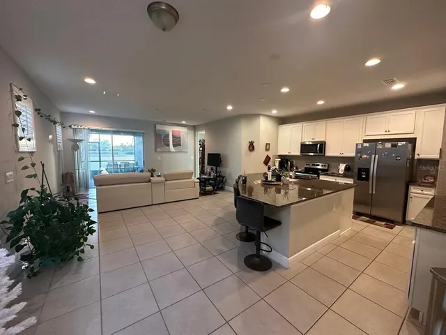 a kitchen with stainless steel appliances kitchen island granite countertop a refrigerator and a sink