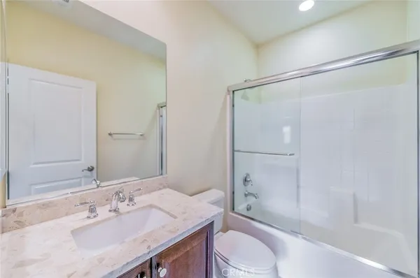 a bathroom with a granite countertop bathtub shower sink vanity mirror and toilet