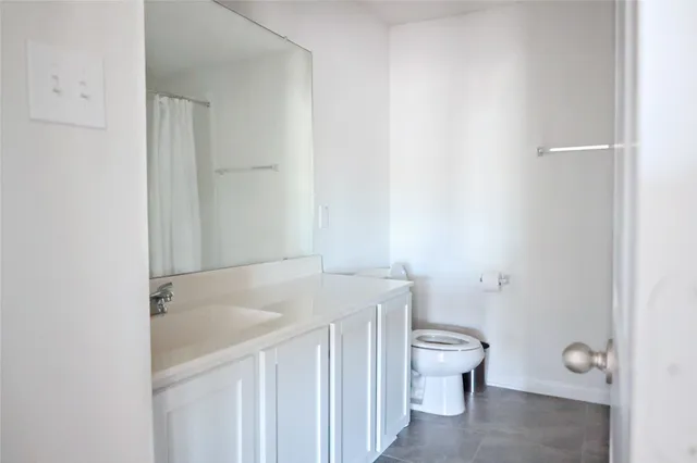 a bathroom with a granite countertop sink toilet and a mirror