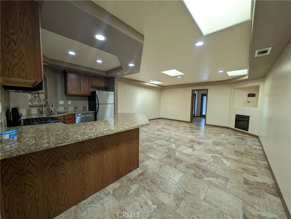 a large kitchen with stainless steel appliances granite countertop a large counter top a stove a sink and a refrigerator