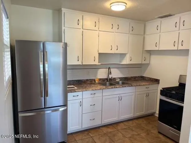 a kitchen with granite countertop a refrigerator sink and cabinets