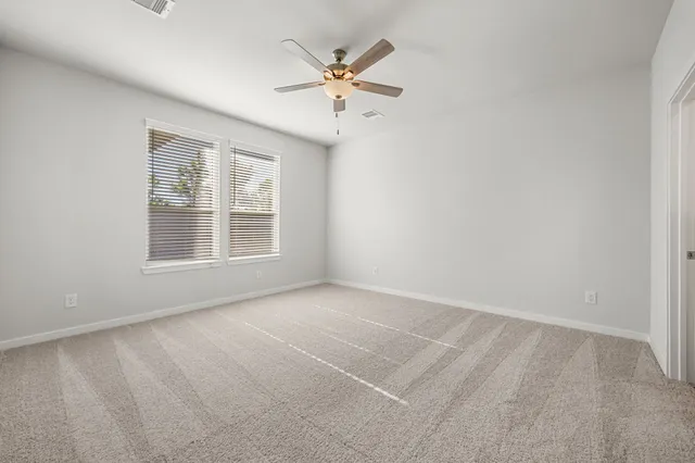 an empty room with ceiling fan and window
