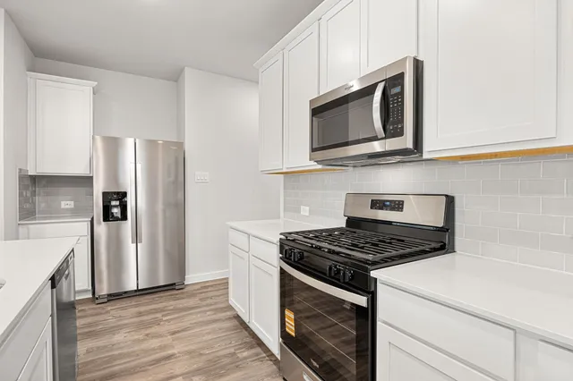 a kitchen with stainless steel appliances a stove a microwave and a sink