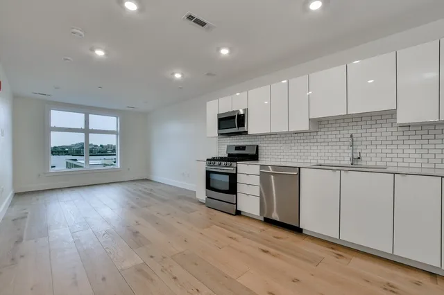 a kitchen with granite countertop wooden floors white cabinets and stainless steel appliances