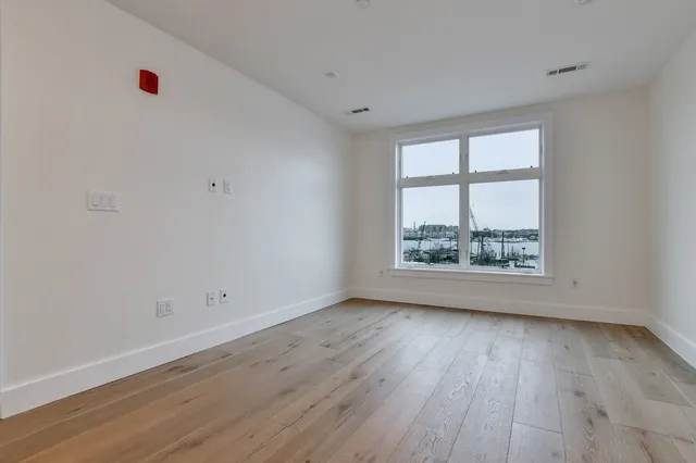 an empty room with wooden floor and window