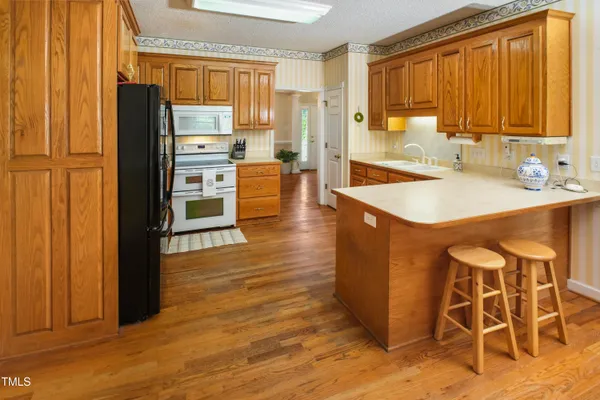 a kitchen with granite countertop a refrigerator a sink dishwasher and wooden cabinets with wooden floor