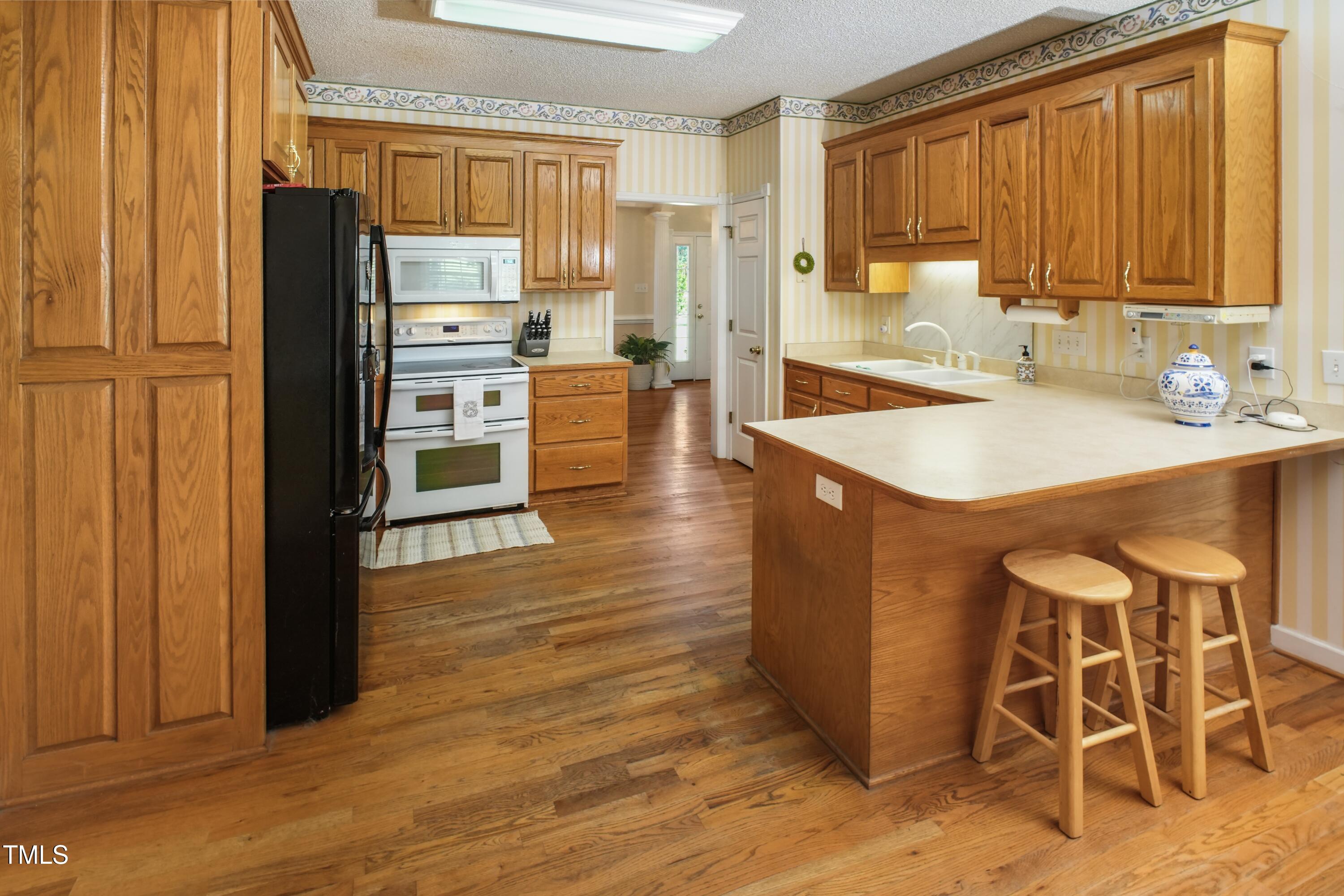 115 Hunters Walk Lane Clinton, NC 28328 - Photo 11 of 39 a kitchen with granite countertop a refrigerator a sink dishwasher and wooden cabinets with wooden floor