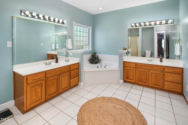 a spacious bathroom with a double vanity sink mirror and bathtub