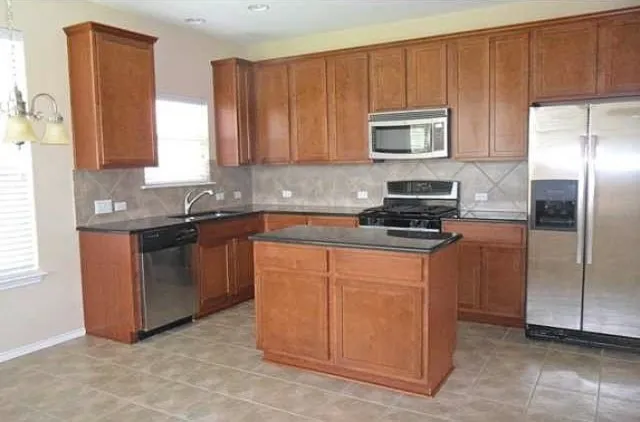 a kitchen with stainless steel appliances granite countertop a refrigerator a stove a sink and a microwave