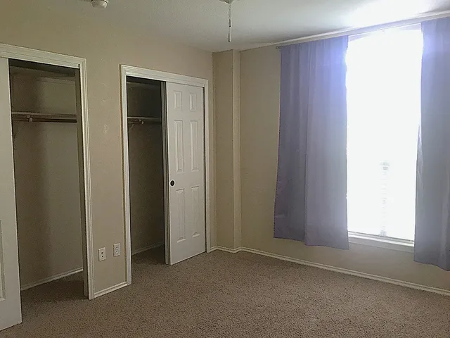 an empty room with windows and closet