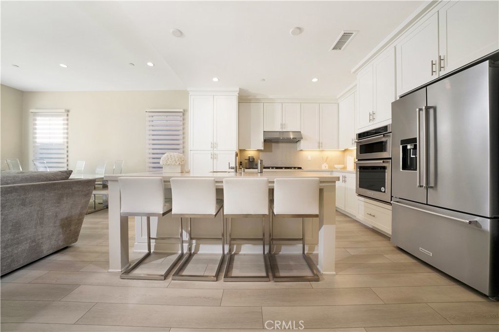 208 Villa Ridge Irvine, CA 92602 - Photo 19 of 46 a kitchen with stainless steel appliances kitchen island granite countertop a table chairs microwave and sink