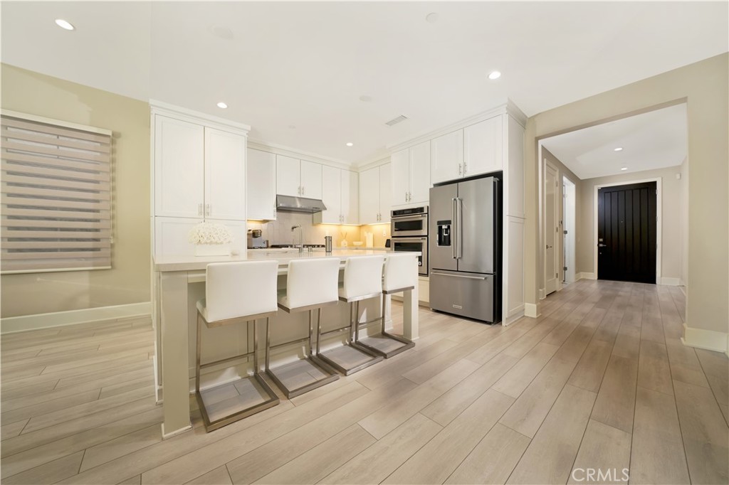 208 Villa Ridge Irvine, CA 92602 - Photo 29 of 46 a kitchen with a refrigerator a stove top oven and white kitchen island with wooden floor