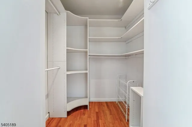 a view of an empty room with wooden floor and closet