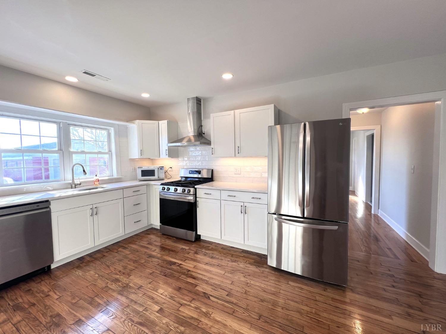 5235 Wards Fork Mill Road Cullen, VA 23934 - Photo 14 of 42 a large kitchen with a refrigerator a sink dishwasher a stove and white cabinets with wooden floor
