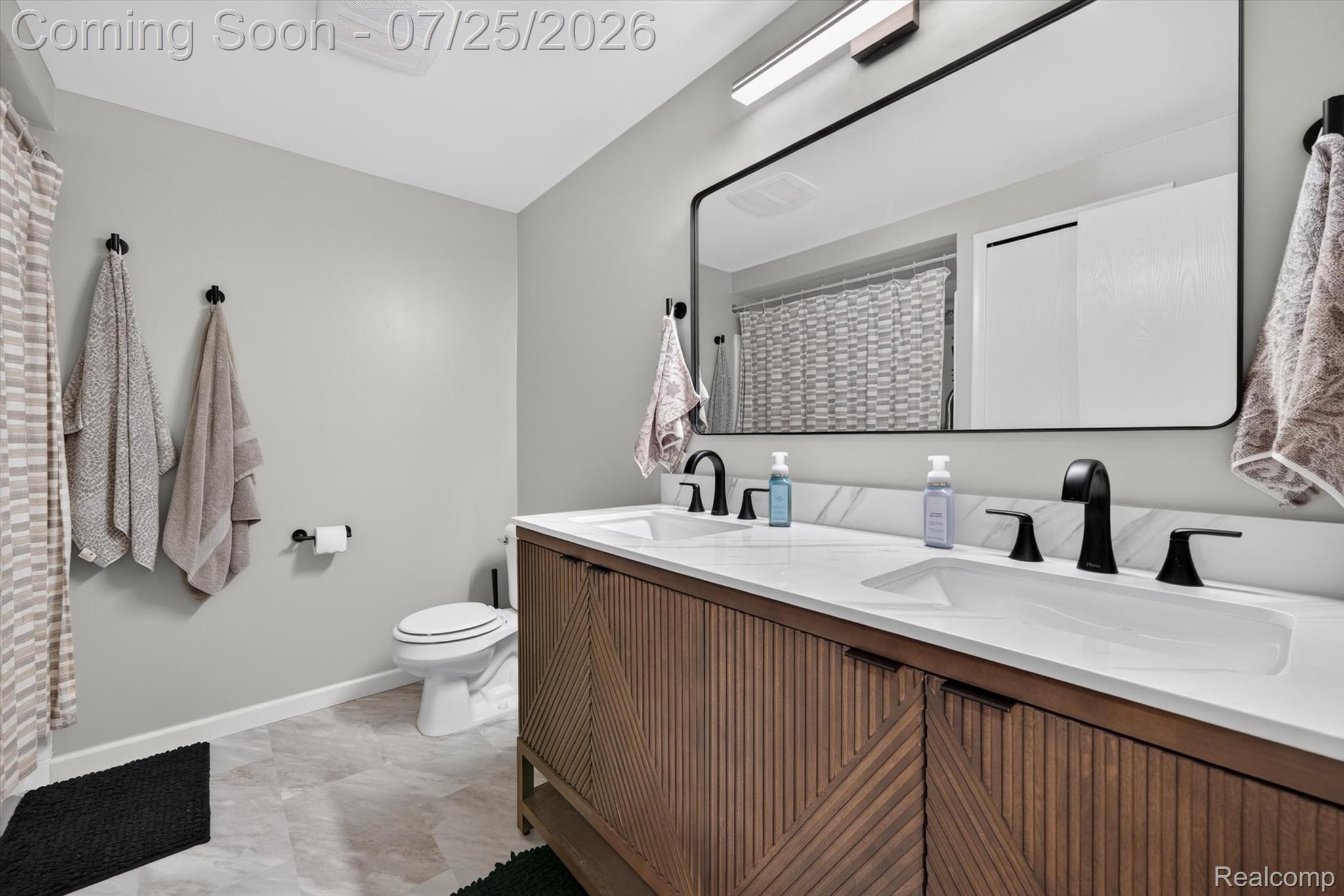 51116 South Foster Road New Baltimore, MI 48047 - Photo 24 of 31 Double vanity with wood-finish cabinetry, integrated white sinks, and matte black fixtures
