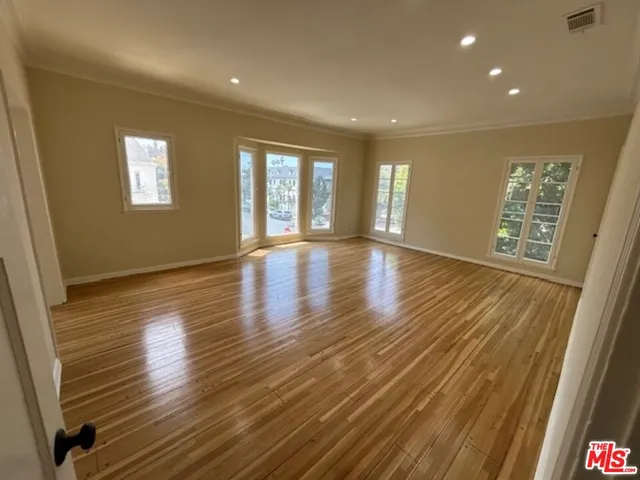 a view of an empty room with wooden floor and a window