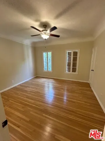 a view of empty room with wooden floor and fan