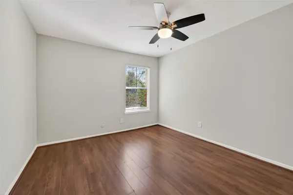 an empty room with wooden floor closet and fan